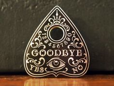 a gold brooch with the words goodbye written in black and white lettering on it