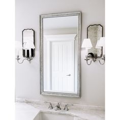 a bathroom sink sitting under a large mirror next to a wall mounted faucet