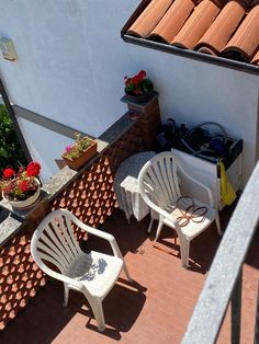 two white chairs sitting on top of a brick patio