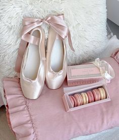 a pair of pink ballet shoes sitting on top of a bed next to a box of macaroons