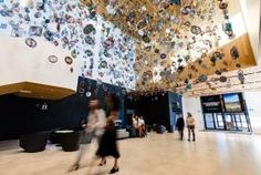 people are walking around in the lobby of a building with many circular objects hanging from the ceiling