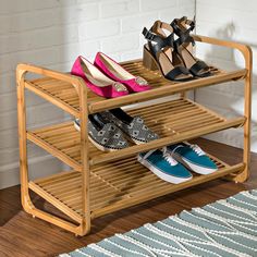 three pairs of shoes are sitting on a bamboo shoe rack