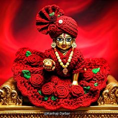 a crocheted figurine sitting on top of a golden chair covered in red roses