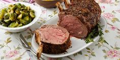 a large roast beef on a plate next to a bowl of brussel sprouts