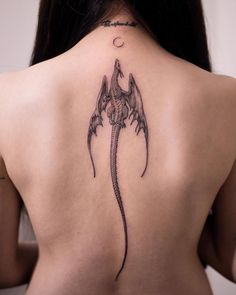 the back of a woman's neck with a dragon tattoo on it