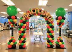 an arch made out of balloons with the word happy birthday spelled in gold and green