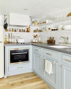 a kitchen with white cabinets and gray counter tops, an oven in the middle is surrounded by dishes