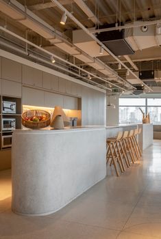 an empty kitchen and dining area in a modern office building with concrete countertops, white walls, and exposed ceiling lights