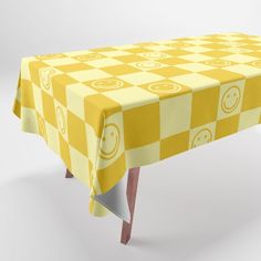 a yellow and white checkered table cloth with smiley faces on it, sitting in front of a white background