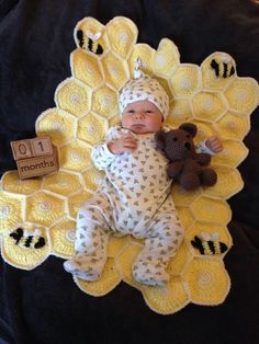 a baby laying on top of a blanket next to a teddy bear and honeycombs