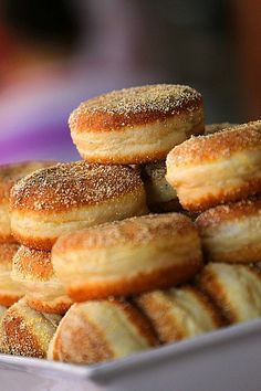 there are many donuts stacked on top of each other in a white plate with sugar sprinkles