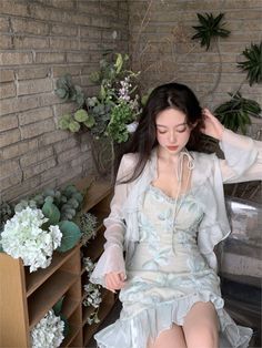 a woman sitting on top of a wooden table next to plants and flowers in vases