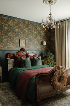 a bed with green and red blankets in a bedroom next to a chandelier