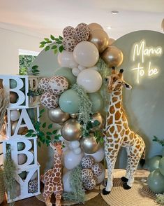 a baby shower with giraffes, balloons and greenery on the wall