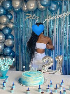 a woman standing in front of a cake and balloons