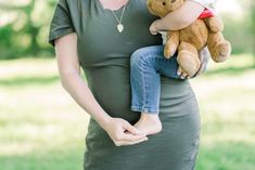 a pregnant woman holding a brown teddy bear