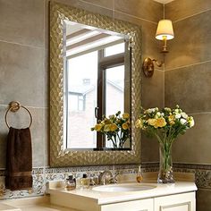 a bathroom with a sink, mirror and flowers in the vase on the counter top