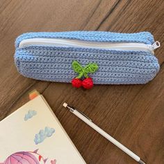 a crocheted pencil case sitting on top of a table next to a notebook