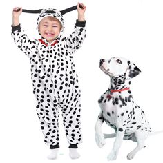 a little boy in dalmatian pajamas standing next to a dog wearing a costume