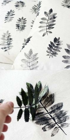 a hand is touching the fabric on a bed with black and white leaf print sheets