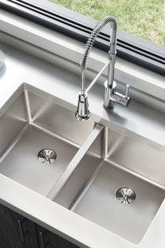 two stainless steel kitchen sinks with faucets in front of a window and grass outside