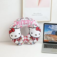 an open laptop computer sitting on top of a desk next to a hello kitty pillow