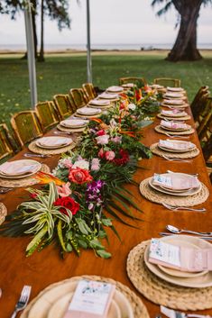 a long wooden table with place settings and flowers on the top, along with plates and napkins