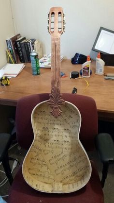 a guitar shaped chair sitting in front of a desk