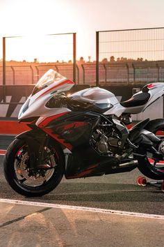 a red and black motorcycle parked on top of a race track