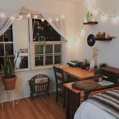 a bedroom with wooden floors and lights strung from the ceiling over the bed, along with a desk