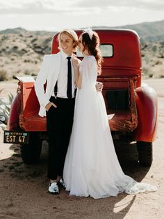 a bride and groom standing in front of an old red truck