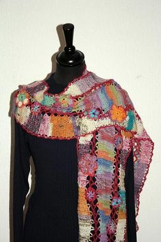 a woman's black top with multicolored crocheted shawl draped over it