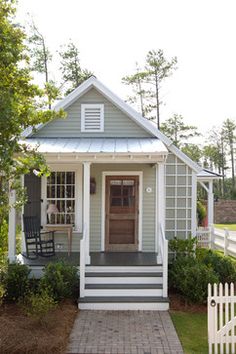 a small gray house with white trim and steps leading up to the front door is shown