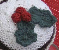 a crocheted christmas ornament with holly leaves on it sitting on a table