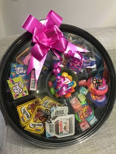 an assortment of candy and candies in a black tray with pink bow on top