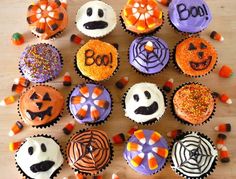 halloween cupcakes with sprinkles and spider web designs are arranged on a wooden surface