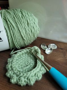 a ball of yarn next to a crochet hook and scissors on a table