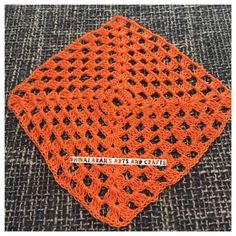 an orange crocheted square on top of a gray carpet with the words afghan arts and crafts written across it