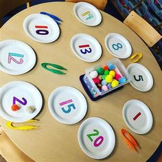 the table has paper plates with numbers on them and plastic candy in front of it