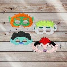 three masks with different designs on them sitting on a wooden surface