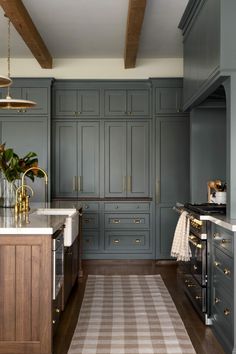 a kitchen with gray cabinets and wooden floors, an area rug on the floor in front of the stove