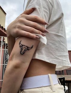 a woman with a bull tattoo on her left arm and the other arm behind her