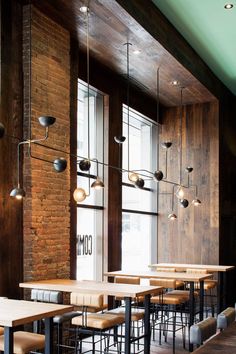 an empty restaurant with tables and chairs in front of large windows that have lights hanging from them