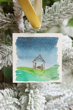 a christmas ornament hanging from a tree with a nativity scene on it