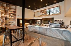 the interior of a coffee shop with tables and stools