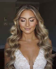 a woman with long blonde hair wearing a wedding dress and makeup looks down at the camera