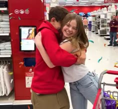 two people hugging each other in front of a red shopping cart at a target store