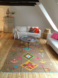 a living room with white couches and colorful rugs on the wooden flooring