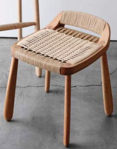 two wooden chairs sitting next to each other on cement floored area with wall in background