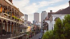 a city street lined with tall buildings and lots of greenery on the balconies